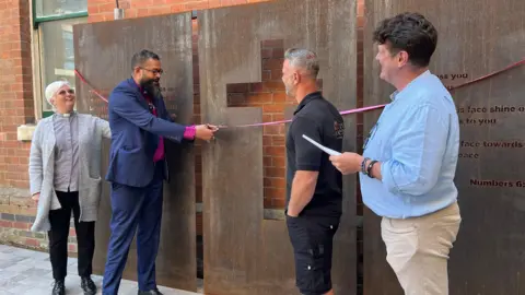 Bishop Saju, cuts the ribbon alongside the Vicar of Holy Trinity Church, Elaine Sutherland, and Alistair Hudson, the former CEO of East Midlands Sexual Health formerly known as LASS.   