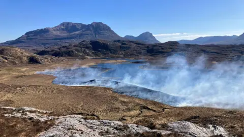 The Assynt Foundation A mountain landscape with clouds of smoke in the distance 