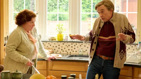 Alan Partridge in his kitchen talking to his assistant, Lynn Benfiel (Felicity Jane Montagu)