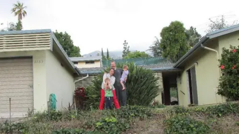 Sian McArdle A couple standing in the front garden holding two young children