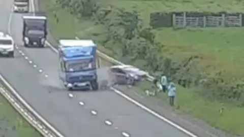 A lorry crashing into a car on the side of a dual carriageway