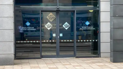 Front door of the Jersey Financial Services Commission's headquarters in St Helier. They are glass doors with the organisation's logo on them.