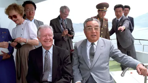 Former President Jimmy Carter and,. behind him, former First Lady Rosalynn Carter with Kim Il Sung aboard the North Korean leader's yacht during their 1994 visit to Pyongyang. (SINGLE USE ONLY. DO NOT REUSE)