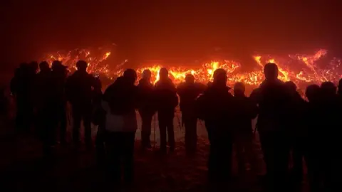 Line of people standing in front of lava flow