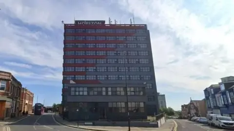 High-rise flats in the middle of two streets. The sign Horizon is visible at the top of the building. 