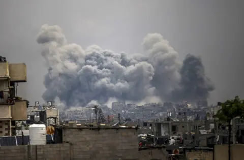 Anadolu/Getty Images A huge smoke cloud rises above buildings in Gaza City. 