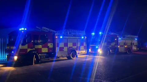 Three fire engines sit near the scene of the fire 