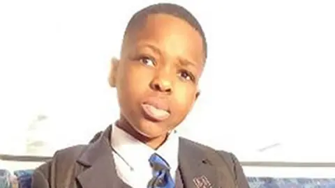Daniel Anjorin pictured sitting on a bus wearing school uniform  