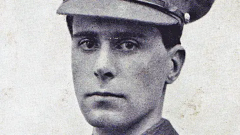 Essex Cricket Club A grainy black and white photo of Geoffrey Davies. He has short hair and is wearing Army officer uniform including a peaked cap.