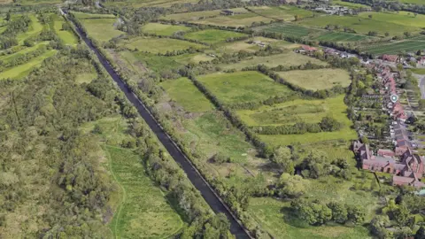 Google An area of green land with trees, and houses to the right