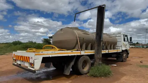 A water tanker fills up at a large municipal tap which reaches over it in Hammanskraal