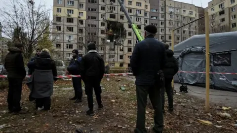Reuters Residents stand near apartment buildings hit during the Russian drone strike, amid Russia's attack on Ukraine, in Dnipro, Ukraine, November 8, 2025.