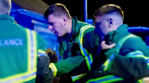 Paramedics at night look down to the ground surprised