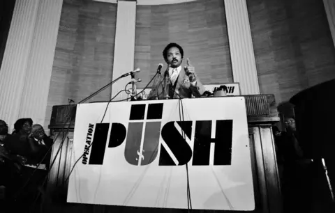 Getty Images Jackson addressing people from a podium at PUSH. 