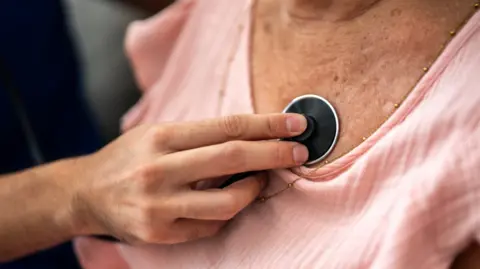 Medic using stethoscope on woman