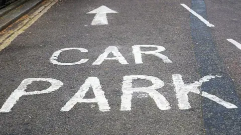 A road with the words "car park" written on it with an arrow pointing ahead.