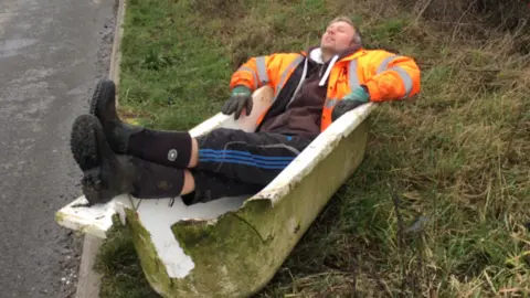 Leicestershire Litter Wombles A man lying in a broken bath dumped at the side of the road