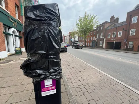 Black plastic covers a parking meter on London St in Reading. It is next to an empty parking bay. 