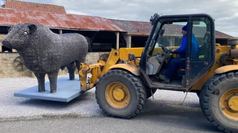 Steven Nesbitt lifts up his giant metal bull with his tractor.