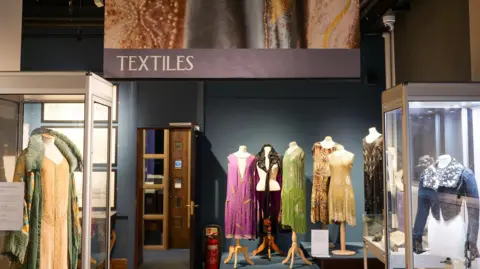 A collection of period costumes displayed inside a museum.