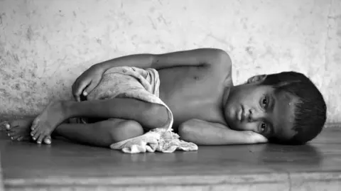 A 2010 photo of seven-year-old Sharanya lying on a cement slab outside her house in Kasargod.