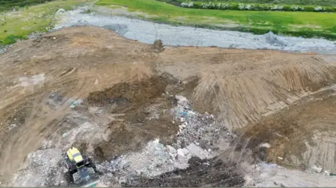 Environment Agency A drone image above the Hills waste site at Lower Compton, Calne, with waste being moved by a yellow digger.