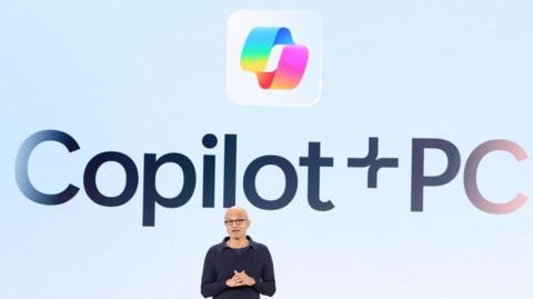 Satya Nadella on stage in front of a large Copilot+ logo