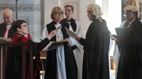 Reuters Dame Sarah stands with clergy who are reading to her during the ceremony