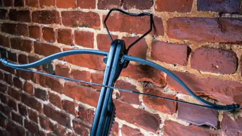 Getty Images A crossbow resting against a brick wall