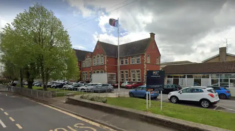 Google A school building with cars parked outside, and a bus stop