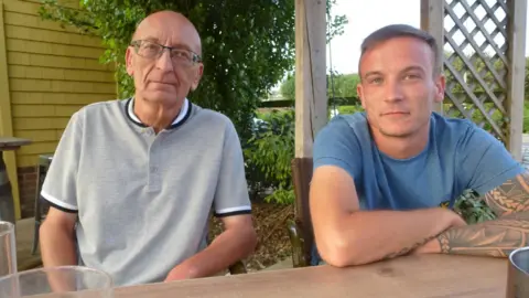 Supplied Christopher Cooper is on the left, wearing glasses and a grey short sleeve top. His son Freddie is on the right wearing a blue T-shirt.