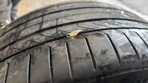 BBC/ Alex James A small sharp piece of metal is sticking out from the middle of a black tyre 
