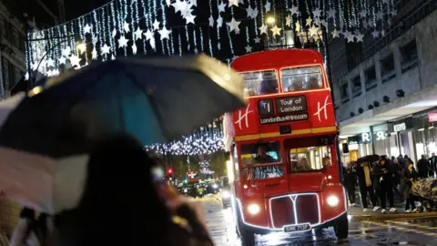 EPA/Shutterstock Red Routemaster London bus - with Tour of London on its destination board - drives down Bond Street at night, with Christmas lights in the background