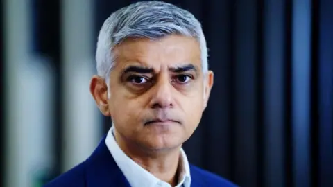 PA Media A close shot of Sir Sadiq, wearing a blue suit, looking into the camera with a neutral expression