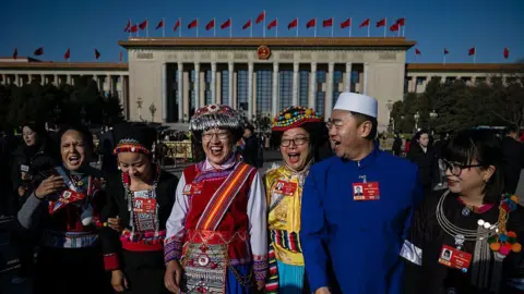 Delegates wearing traditional clothing react at the closing session of the Chinese People's Political Consultative Conference (CPPCC) at the Great Hall of the People on March 11, 2026 in Beijing