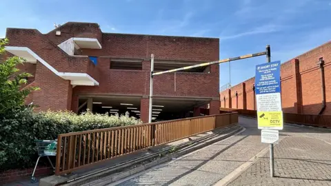 Wharf Road car park. It is built from red brick and has a curved ramp on the side with a brick wall next to it.