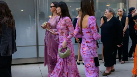 Getty Images Women extracurricular  Pat Bo's New York amusement   wearing pinkish  and purple floral dresses 