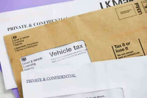Getty Images 3 letters, two white ones with 'Private & Confidential' and one brown letter from DVLA about Vehicle Tax.