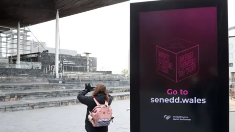 Reuters A person takes images beside an election information sign outside of the Senedd