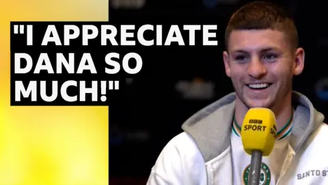 Callum Walsh smiling holding BBC Sport yellow microphone