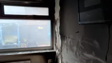 Christine and Neil Clayton The inside walls of a bedroom have been blackened and the paint is peeling off. 