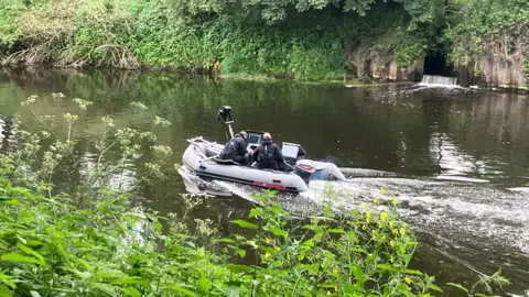 Phil Bodmer/BBC A dinghy with rescue teams inside on a river in South Yorkshire 