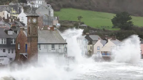 Getty Images Coastal village during a storm, with waves smashing up on the houses.