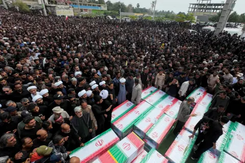 Reuters An image showing a large crowd gathering at a funeral on 3 March for the victims of the attack. Several coffins can also be seen in the image - some child-sized - with the flag of the Islamic Republic draped over them.