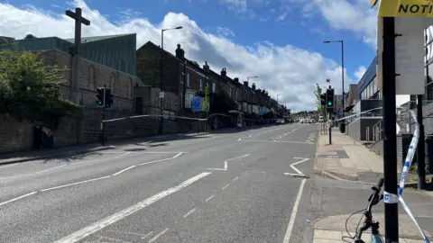 Mark Ansell/BBC An empty road with a police cordon in place.