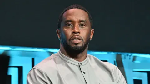 Sean Diddy Combs wears a grey shirt and has a blank expression