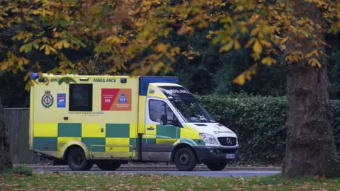 An South Central Ambulance Service ambulance parked next to a park.