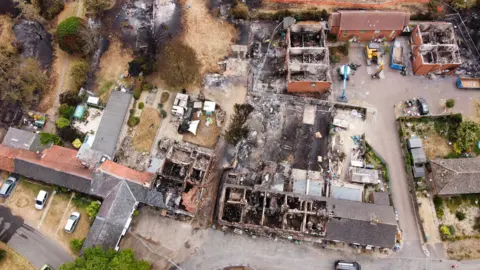 An aerial view of homes wrecked by fire. Roofs are missing and the insides of homes are black. 