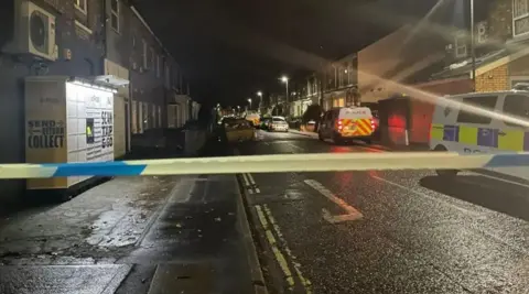 Vyner Street in the Haxby Road area of York with a police cordon in place. Police vehicles are parked down the right-hand side of the street, with police tape stretched across the road.