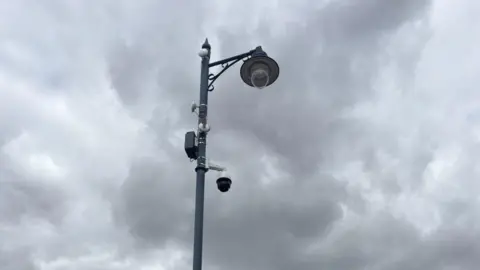 Jaimielee Rendall/BBC A Camera is at the top of a lamp post. 